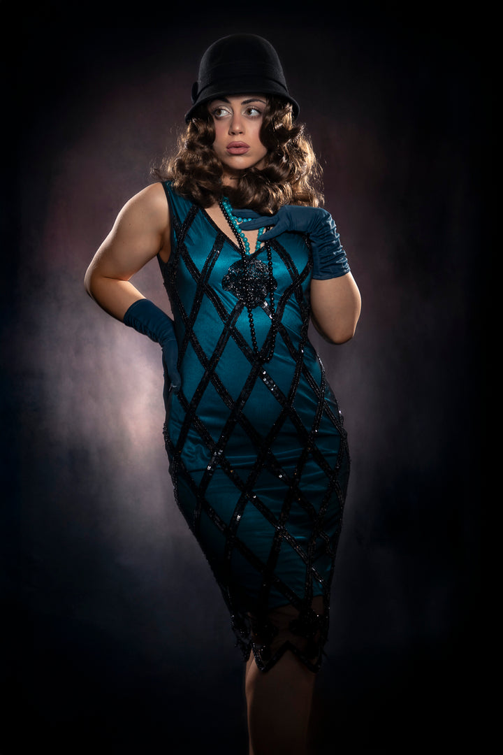 Catherine Biggs 1920s costume – teal satin flapper dress with black sequin detail, teal gloves, beads and cloche hat, available to hire at Little Shop of Horrors Costumery.